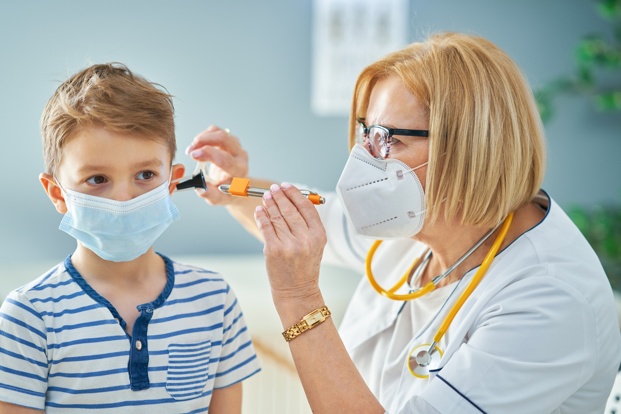 Pediatrician doctor examining little kids in clinic ears check